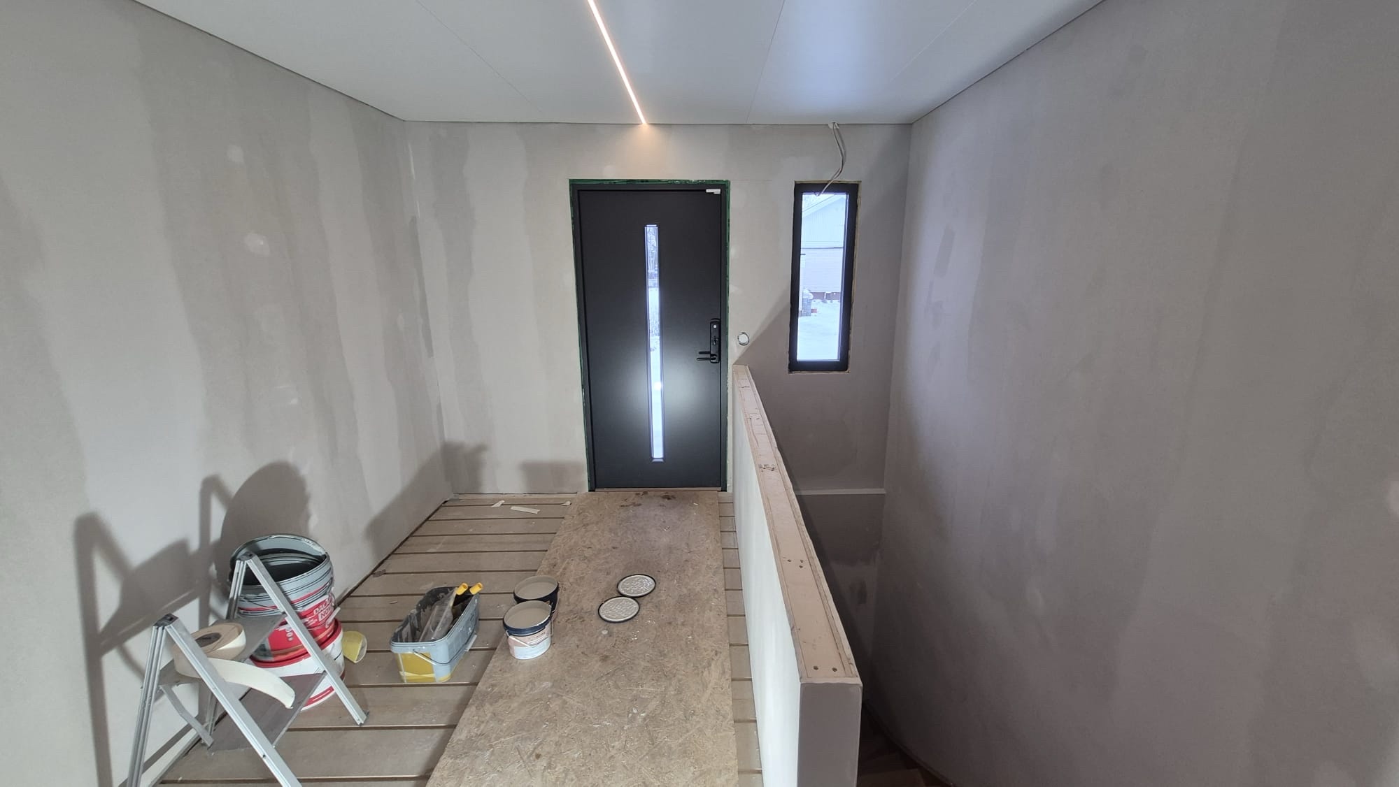 Hall före målning med spacklade gipsväggar och byggmaterial
