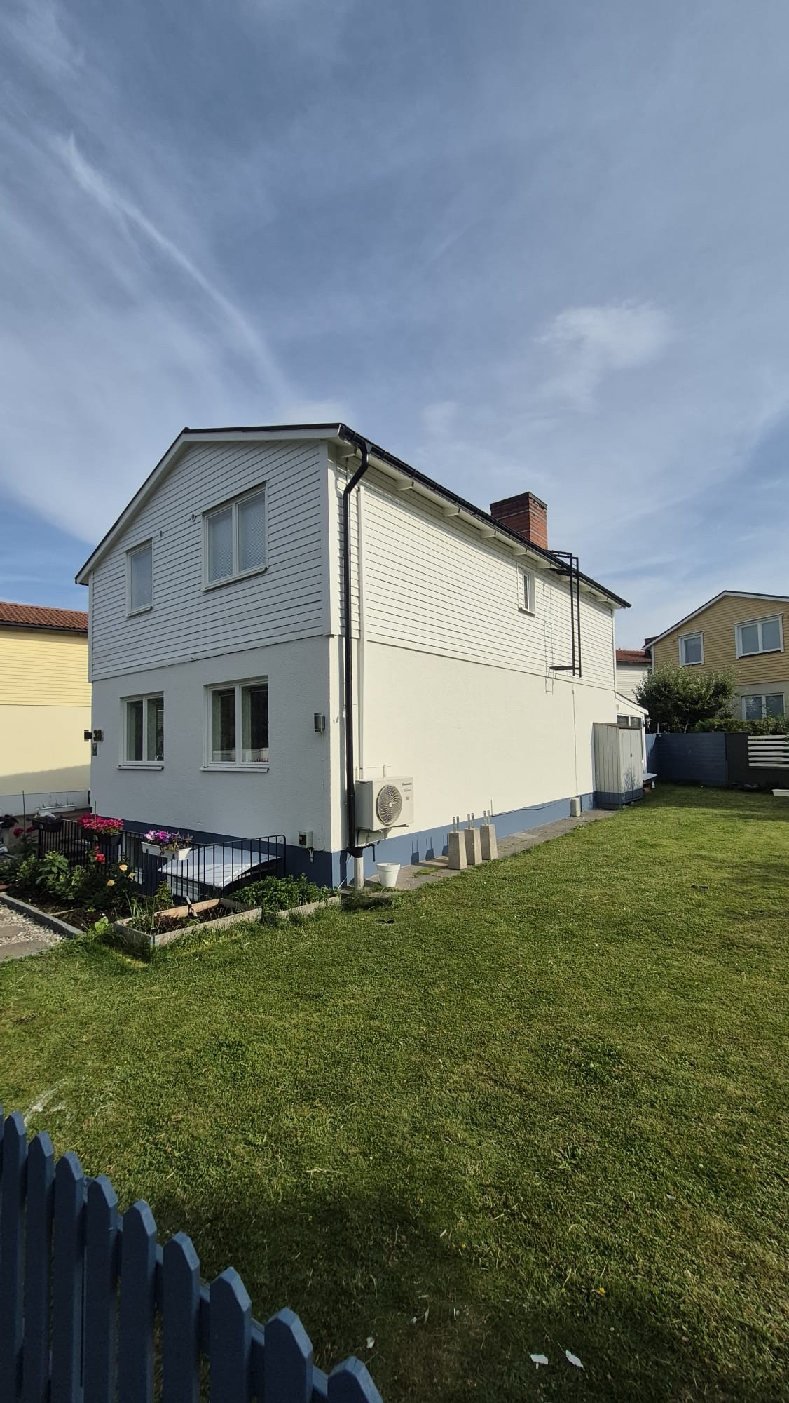 Samma villafasad efter målning i vitt med blå sockel