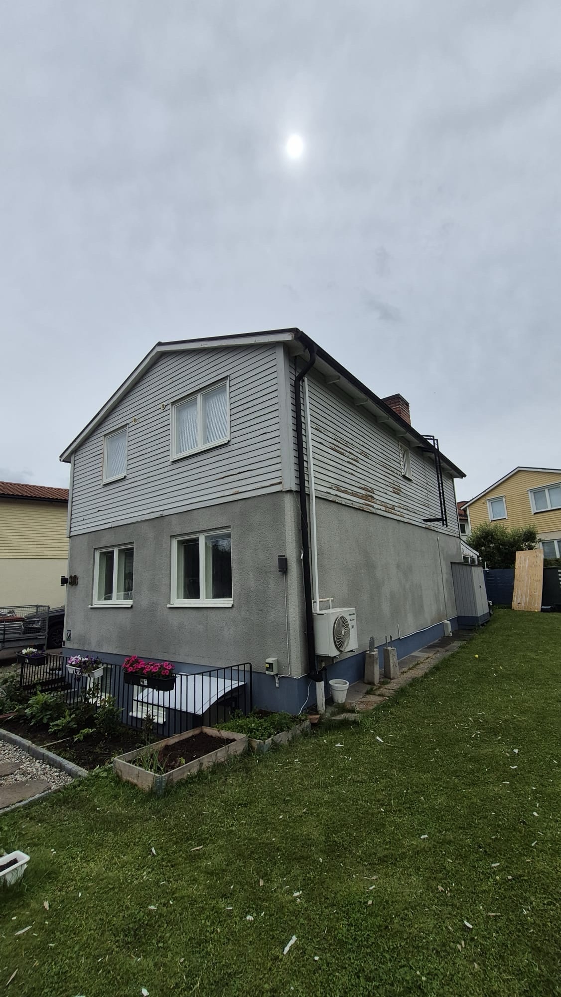 Villafasad före målning med sliten grå puts och panel